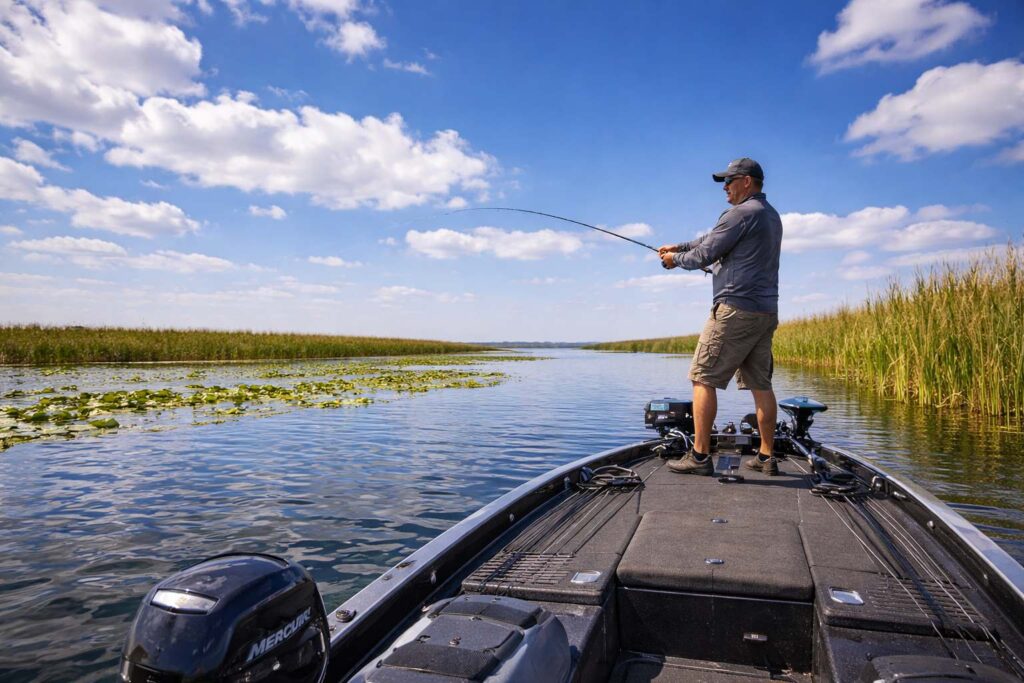 10 Best Bass Fishing Lakes in Florida for Trophy Fish and Year-Round Action Make a image man standing on a bass boat getting casting his fishing rod they got a nice beautiful blue sky day