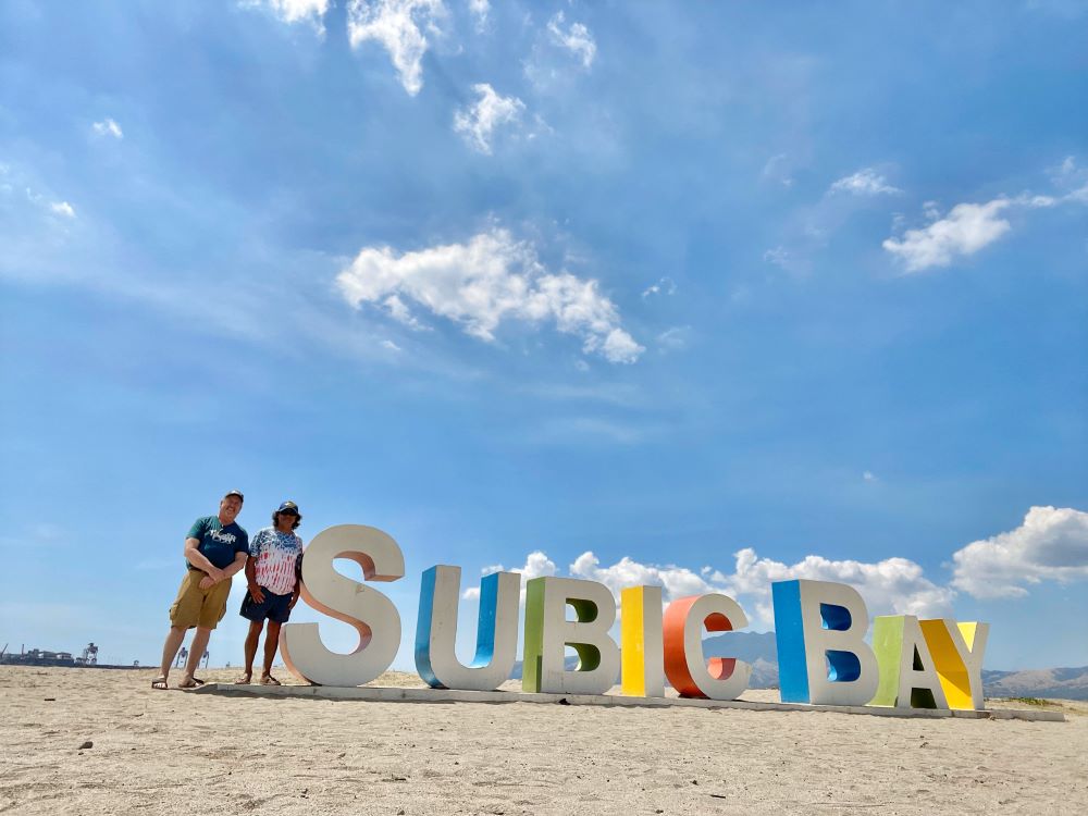 Guy Wann and Jeff Hass standing by Subic Bay sign